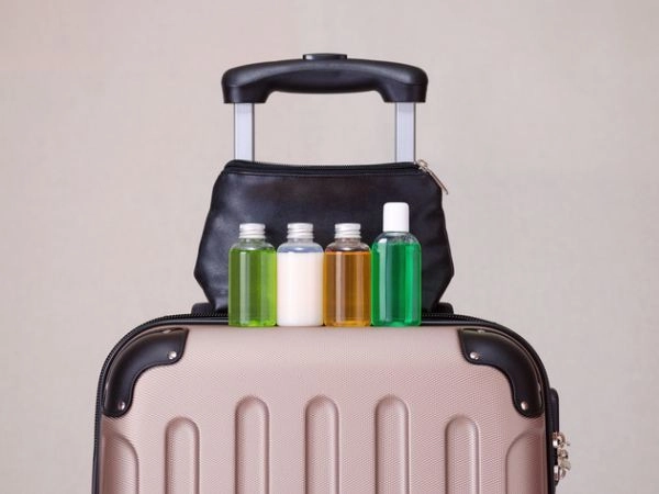Articoli da toeletta da viaggio in piccole bottiglie di plastica sulla valigia
