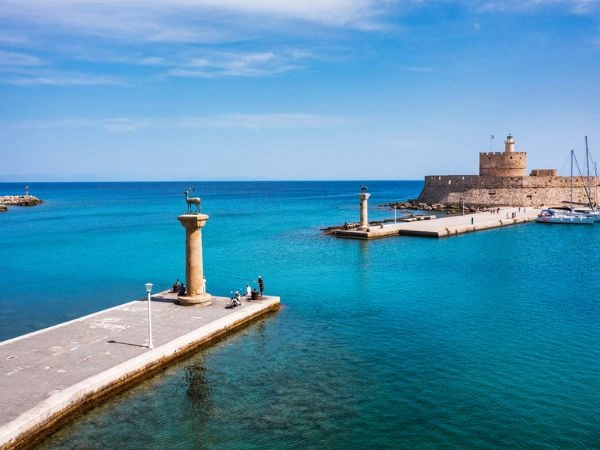 Fortezza di Agios Nikolaos con yacht nel porto di Mandraki al tramonto, Rodi Grecia