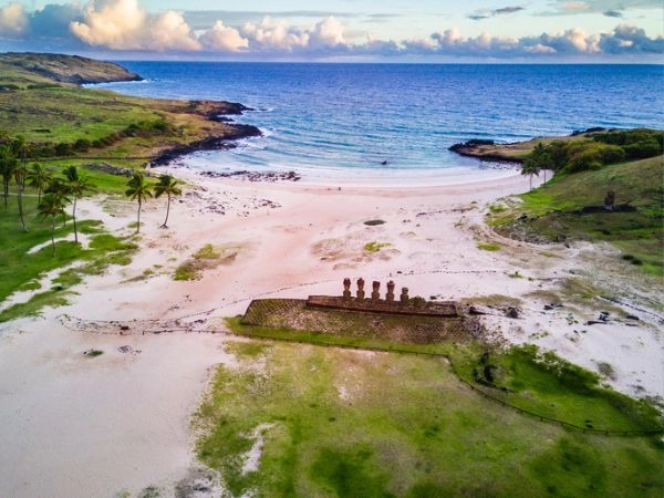 Spiaggia tropicale moai, palme, sabbia bianca e acque cristalline.